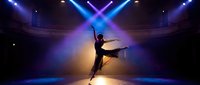 Young female ballet dancer in silhouette performing arabesque on stage with dramatic blue and golden lighting, neon cross pattern overhead, professional theater setting for dance performance.