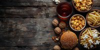 Fast food burger with french fries, popcorn and cola drink on rustic wooden background. Perfect for restaurant menu, food delivery service or casual dining promotion.