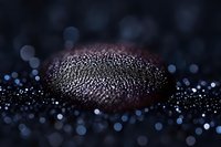 Macro shot of water droplets on dark surface creating abstract pattern with bokeh effect in background, mysterious atmospheric composition in blue tones.