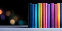 Colorful chalk pastels arranged in rainbow order standing vertically against dark background with bokeh lights, creating artistic composition for drawing and education.