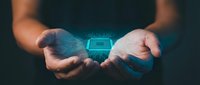 Hands holding glowing blue microchip with circuit board pattern against dark background. Represents technology innovation, artificial intelligence, and digital transformation for business and computing concepts.