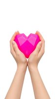 Hands cupping bright pink geometric heart shape on white background isolated for charity healthcare love concept design.