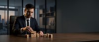Professional businessman in dark suit arranging wooden blocks on desk in modern office with city view, strategic planning and business development concept.