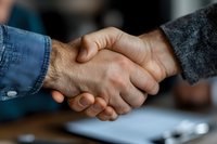 Close-up of two male business professionals shaking hands during meeting, symbolizing partnership, agreement, and trust in professional environment.