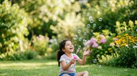 Young girl with dark hair and medium skin tone blowing soap bubbles outdoors in a lush garden setting during daytime, surrounded by blooming flowers and green foliage, perfect for childhood, happiness and summer themes.