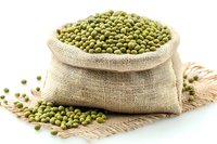Raw mung beans in burlap sack on white background, organic legumes for healthy cooking and plant-based protein source.