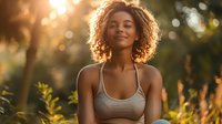 Young African American woman with curly hair smiling peacefully in golden sunset light, surrounded by nature, radiating happiness and tranquility.