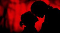 Romantic couple silhouettes in intimate moment against dramatic red lighting creating passionate atmosphere for love and relationship concepts.