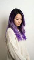 Young Asian woman with purple ombre hair wearing cream sweater looking down peacefully against neutral background for beauty and lifestyle content.