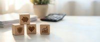 Wooden blocks with insurance icons including umbrella, shield, heart and growth chart on white desk for business protection concepts.