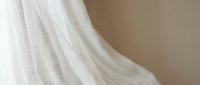 Soft white flowing fabric with delicate texture and gentle folds creating elegant drapery against neutral background for interior design projects.
