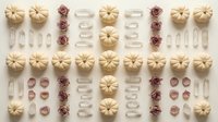 Autumn flat lay pattern with white pumpkins, dried roses and leaves arranged in geometric grid on neutral background for seasonal design projects.