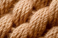 Close-up macro shot of natural beige jute rope texture showing twisted fibers and detailed woven pattern. Organic material background for rustic design projects.