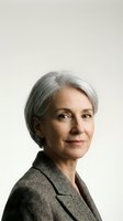 Mature woman with gray hair wearing gray blazer, professional headshot against neutral background, suitable for corporate, business, and executive portraits.