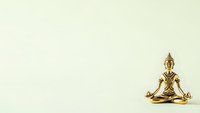 Golden Buddha statue in meditation pose on neutral background for spiritual wellness and mindfulness designs.