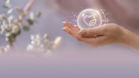 Hand holding glowing heart icon with sparkling light effects and blurred flowers in background, representing love, care, wellness, and digital connection for healthcare and charity concepts.