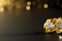 Luxury diamonds and gemstones on dark background with golden bokeh lights creating elegant atmosphere for jewelry advertising.