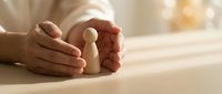 Protective hands cupping wooden figure symbolizing care, security and human resources management in warm office setting for business concepts.