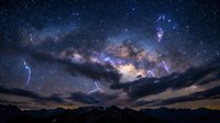 Lightning strikes illuminate mountain landscape under spectacular Milky Way galaxy with vibrant cosmic colors and starry night sky for astronomy backgrounds.