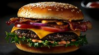 Juicy bacon cheeseburger with melted cheddar, fresh lettuce, tomato, and red onion on sesame seed bun against dark background.