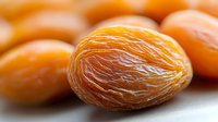 Fresh dried apricot macro shot showing natural texture and wrinkles of preserved fruit against blurred background of more apricots, healthy snack concept.