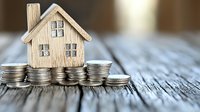 Wooden miniature house model sitting on stacks of silver coins representing real estate investment, mortgage savings, property financing concept.