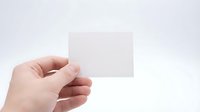 Hand holding blank white card or paper against neutral background, suitable for business presentations, marketing mockups, and promotional designs.