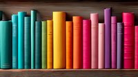 Colorful books arranged in rainbow order on wooden shelf, spines showing gradient from turquoise through yellow, orange, and pink to purple, creating vibrant library display.