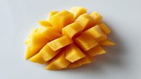 Fresh ripe mango slices arranged in decorative pattern on white background, tropical fruit cut into cubes ready for healthy snacking and culinary use.
