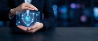 Businessman in dark suit holding glowing digital shield with lock icon, representing cybersecurity, data protection, and network security solutions for enterprise systems.