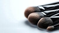 Professional makeup brushes arranged in diagonal composition on light background, showing soft synthetic bristles in brown tones for cosmetic application.