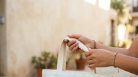 Woman's hands holding white ribbon on gift box, wrapping present for celebration, holiday or special occasion event.
