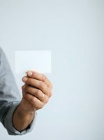 Male hand holding blank white card against neutral background, suitable for business messaging, promotional campaigns, and corporate communications.