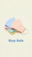 Pastel colored fabric face masks stacked on beige background with Stay Safe text, health protection concept.