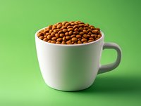 White ceramic cup filled with roasted coffee beans against green background, minimalist composition with dramatic lighting and sharp details for food and beverage marketing.