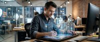 Young male professional of mixed ethnicity working with holographic digital interface at modern office desk, representing technology innovation and future workplace solutions.