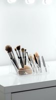 Professional makeup brushes and beauty blenders organized in clear acrylic organizer on white vanity table for cosmetic storage and bathroom decor.