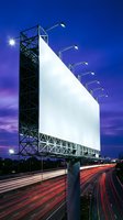 Large blank billboard with illuminated lights at dusk over highway with car light trails for outdoor advertising campaigns and marketing displays.