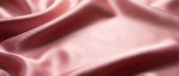 Luxurious pink silk fabric with elegant folds and soft lighting creates sophisticated textile background for fashion and beauty projects.