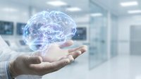 Digital brain hologram floating above open palm in modern medical facility representing artificial intelligence and neuroscience innovation.