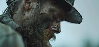 Weathered middle-aged Caucasian man with rugged beard and cowboy hat in dramatic moody lighting, profile view showing intense expression and gritty western atmosphere.