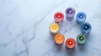 Colorful candles arranged in circle on white marble surface creating rainbow pattern for relaxation meditation spa wellness aromatherapy home decor.