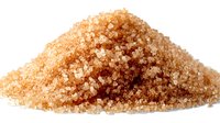 Heap of raw brown sugar crystals on white background, isolated for food packaging design and culinary content.