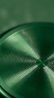 Green metallic surface with circular concentric rings pattern creating radial brushed texture for modern design backgrounds and technology concepts.