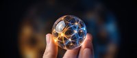 Hand holding glowing geometric sphere with interconnected network nodes representing global connectivity, technology innovation and digital transformation concepts.