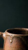Rustic clay pottery vessel with textured surface and natural earth tones against dark background for artisan crafts and traditional ceramics projects.