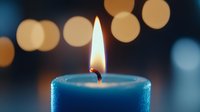 Glowing blue candle flame with soft bokeh lights in background creates peaceful ambiance, perfect for meditation, spa, or wellness concepts.