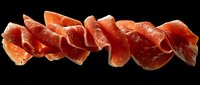 Sliced cured meat arranged in overlapping rows on black background, showcasing texture and color variation of prosciutto or serrano ham for food photography and culinary design.