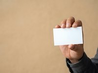Male hand holding blank white business card against neutral beige background, suitable for branding, marketing materials, and corporate design projects.