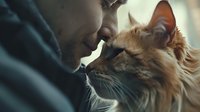 Young African American man tenderly touching noses with ginger cat in intimate bonding moment, showing emotional connection between pet owner and feline companion.